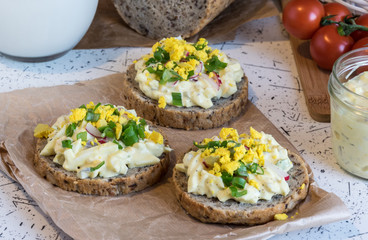 egg spread on round fresh homemade bread, decorated with spring onion and crushed yolk