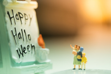 Halloween Concept. Mother and children miniature figures standing in front of halloween night party...
