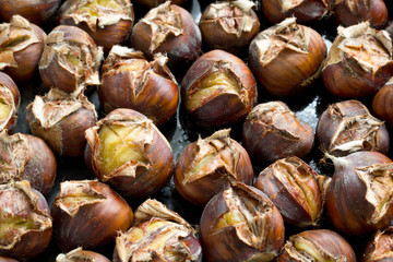 Group of freshly roasted chestnuts in baking pan.