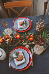 Festive Christmas and New Year table setting in red and grey tones. Dining place for celebration with handmade rustic details and candles