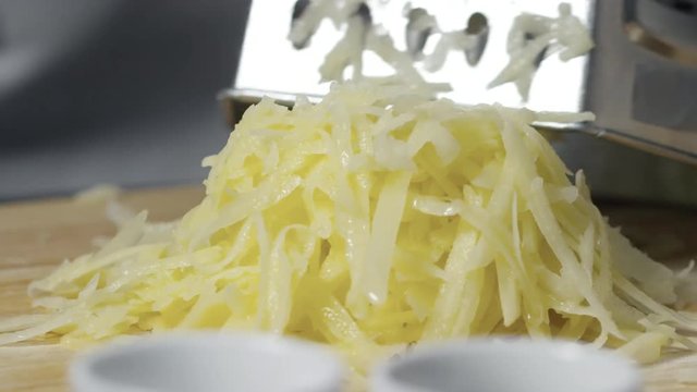Close up of hand of unrecognizable person grating raw potato on metal grater