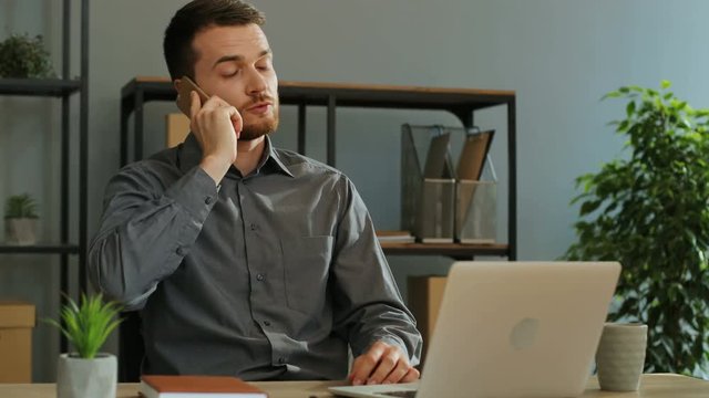 Portrait shot of handsome business man having important conversation with business partner on the smart phone in the stylish office.