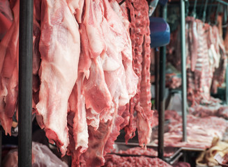 Fresh pork fillet hanging on display for sale at the butcher shop.

