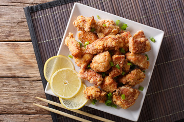 Portion fried chicken karaage with lemon and onion close-up on a plate. Horizontal top view