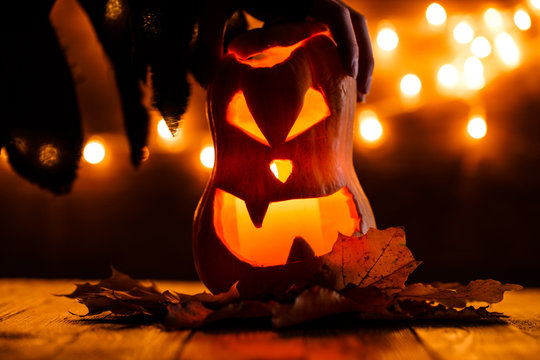 Photo of halloween pumpkin cut in shape of face with witch's hand