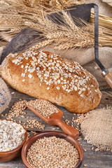 Bread from rye and healthy grains on an old rustic table with a sickle in the background