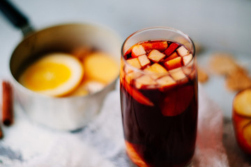 Hot mulled wine in a glass with orange slices, anise and cinnamon sticks, star cookies on vintage...