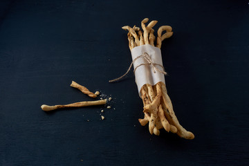 Traditional Italian snack, bread - grissini. On a dark stone table, background with free text space.