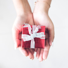 Woman's hands give present give wrapped christmas or other holiday handmade gift box.
