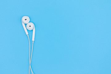 Top view of White Earphones on Blue background. Copy space. Music is my life concept