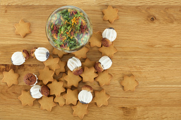 Delicious cookies and tea leaves in glass jar on wooden table