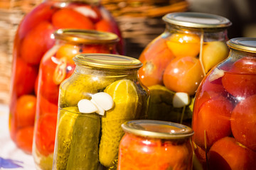 canned cucumbers and tomatoes in glass jars