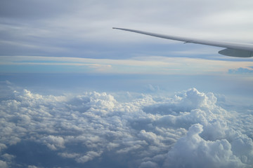 View of beautiful cloudscape with shades of blue sky background from flying plane window with airplane wing