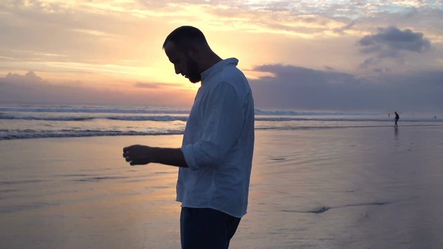 Silhouette of sad, depressed man on beach during sunset, super slow motion 240fps
