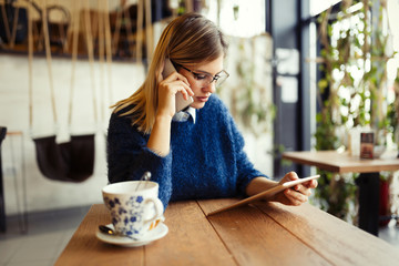Beautiful young woman using digital tablet at coffee shop