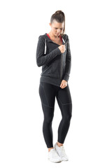 Young attractive sporty female runner get dressed preparing for training. Full body length portrait...