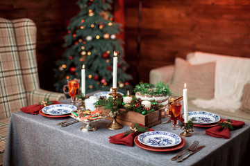 Beautiful Christmas family dinner table at the nicely decorated New Year interior with Christmas tree
