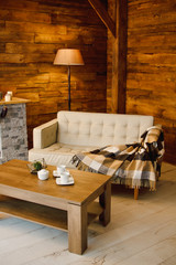 Home comfort. Armchair near the fireplace with firewood. Photo of interior of room with a wooden wall, wreath and garlands, Christmas atmosphere