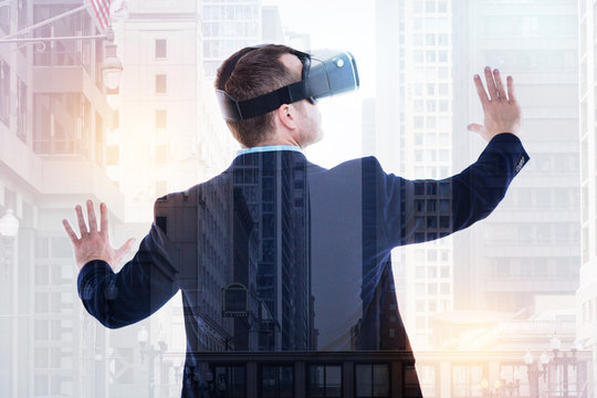 Back view of businessman wearing VR headset and spreading hands