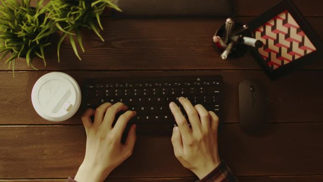 Top down shot of man drinking coffee while typing on keyboard