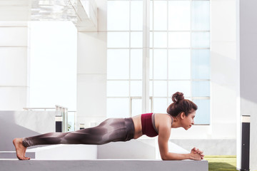 Woman practicing yoga  in front of a large window