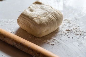 Dough with flour and rolling pin lie on the table