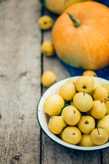 Naklejka na ściany i meble A bowl full of apples and pears next to the orange pumpkin, a senior wooden background