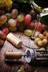 Dry white wine in glass and corkscrew with cork, selective focus