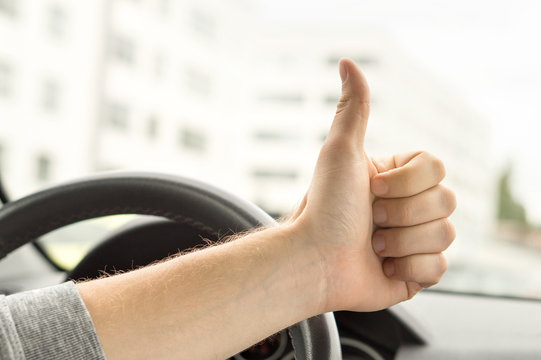 Happy driver showing thumbs up in car. Satisfied with new car or no traffic. Passed driving school test or vehicle inspection. Vehicle fixed and repaired. - Powered by Adobe