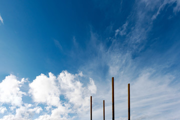 Four poles appear to be soaring into a bright blue cloudy sky