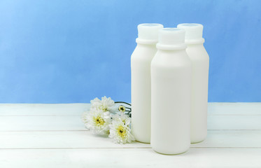A bottle of milk and glass of milk on a wooden table on a  background