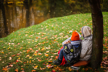 мама читает ребёнку книгу на берегу озера 