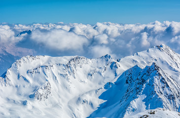 Alpine landscape with peaks covered by snow and clouds