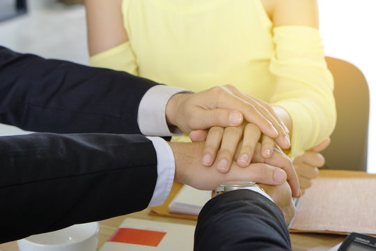 Businessmen and woman holding hands together in the office