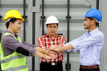 Engineers wearing helmets making agreement by holding hand together at the work site