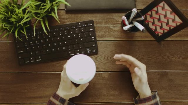 Top down shot of man having video chat and gesticulating while drinking coffee