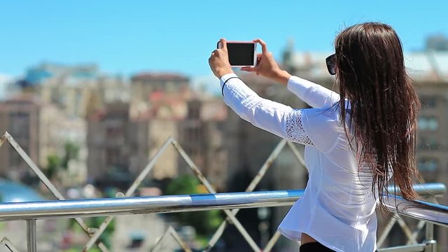 Businesswoman records videos and makes photos on his smartphone. Attractive girl with red cell phone