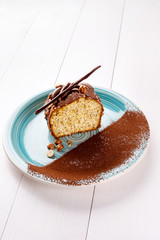 Small cake with different stuffing on a blue plate. White wooden table.