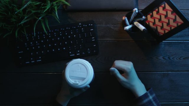 Overhead shot of man having video chat and gesticulating while drinking coffee