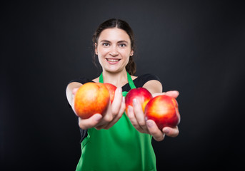 Brunette woman employee giving you nectarine