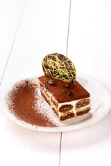 Small cake with different stuffing on a white plate. White wooden table.