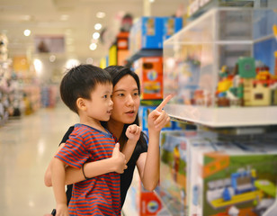 Young Asian mother and her kid shopping toy in shopping mall