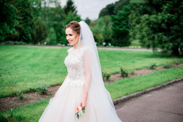 Tender young bride walks in white dress around the park