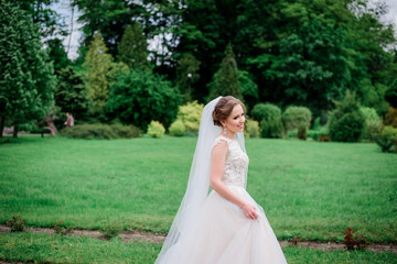 Fototapeta na wymiar Tender young bride walks in white dress around the park