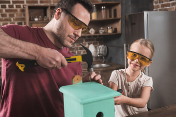 Daughter and father making birdhouse