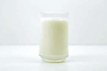 A bottle of milk and glass of milk on a wooden table on a  background