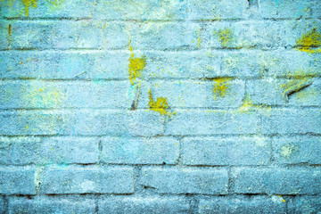 Background and wallpaper or texture of a blue brick wall with stains of yellow paint.