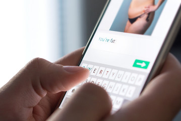 Body shame, cyber bullying and bad behavior online concept. Internet troll sending mean comment to...