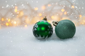 2 green Christmas ball on the background lights garland and faux snow