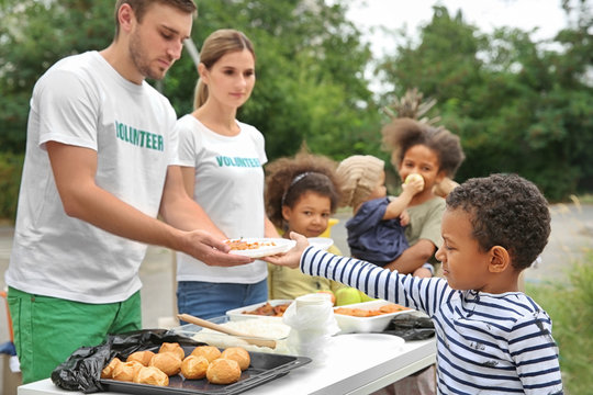 Volunteers sharing food with poor African children outdoors